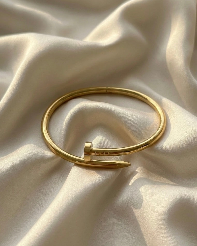 Gold bracelet on a textured beige fabric background