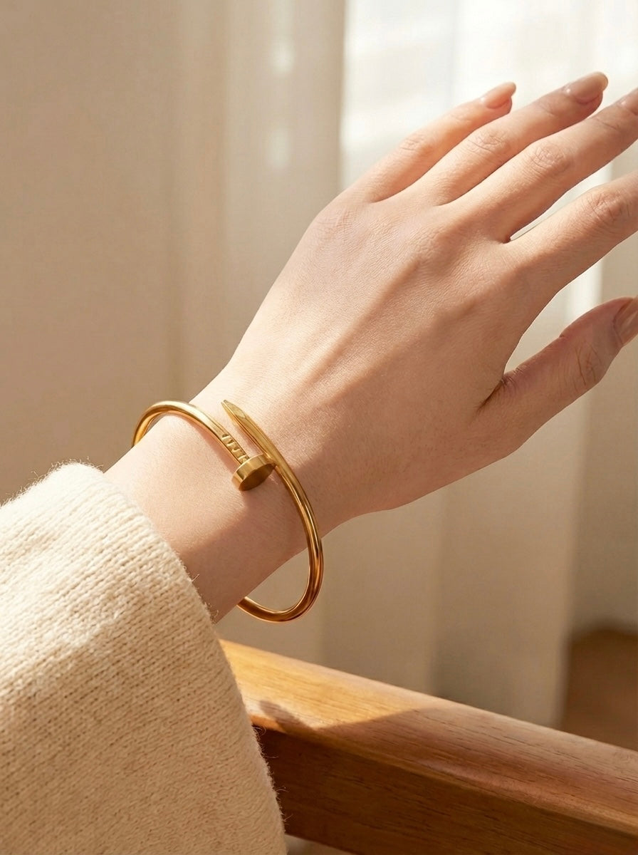 Hand wearing a gold bracelet with a soft background