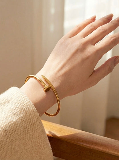 Hand wearing a gold bracelet with a soft background