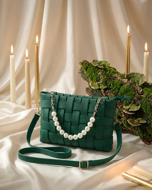 Green woven handbag with pearl strap on a white surface with candles and greenery.