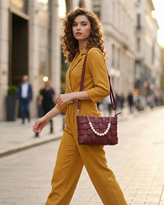 amrea official - Woman in mustard yellow outfit with a maroon handbag walking on a city street.