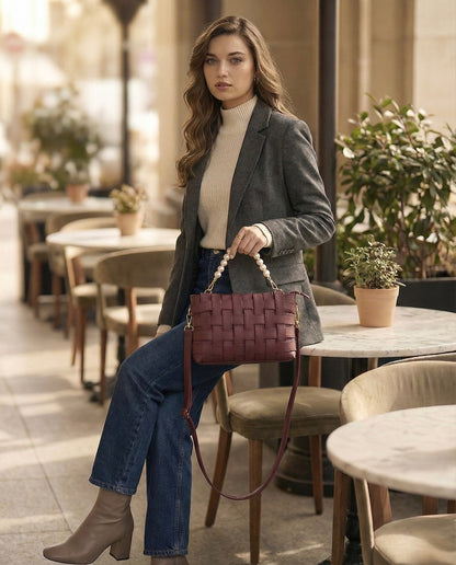 Woman holding a woven handbag in an outdoor cafe setting