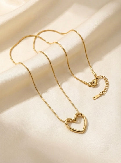 Gold heart-shaped necklace on a beige fabric background